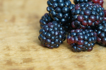 Ripe and juicy blackberries isolated on a wooden background.
