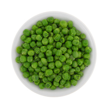 Green peas in a white bowl isolated on a white background.