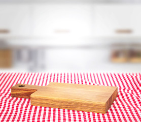 Wooden empty cutting board on picnic cloth background.