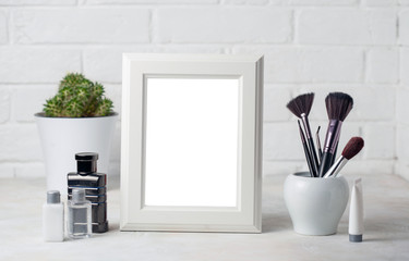 White wooden frame with copyspace and cosmetic brushesh and nail polish. Fahion beauty mockup concept on white Brick wall background.