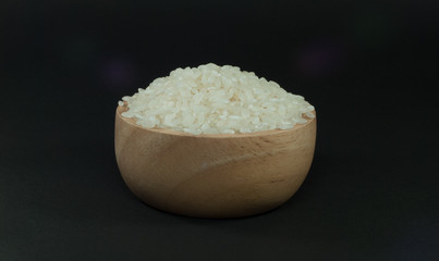 Japanese rice in a wooden cup has a black background.