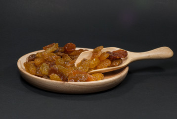 The raisin in the wooden dish has a black background.