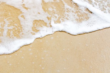 Fototapeta premium top view of soft sea wave on sand at the beach, beach background and summer concept, sunlight effect, copy space