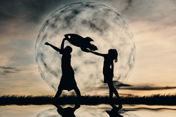 Silhouette boy and girl holding a rocket paper on the sky with moon background  color of vintage tone