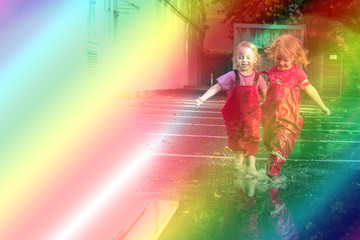 Children play on the street after the rain in pink bright rubber boots. The rays of the sun are reflected in the drops of water
