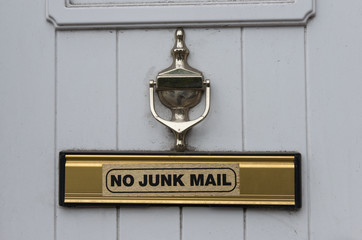 Door knocker and No junk mail sign on letterbox of a white door of a house