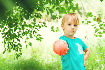 Portrait of cute little boy playing with colorful ball in garden . Sport and vacation concept.