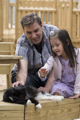 Dad and his daughter playing with a cat outside