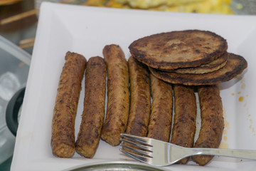 Sausages and burgers just cooked on a outdoor barbecue in the daytime