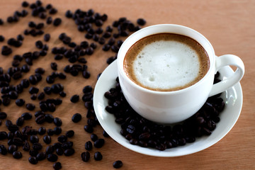 Hot coffee in white cup and coffee beans on the table