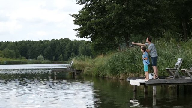 Fisherman with spinning rod catching fish on lake