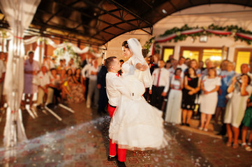 Fototapeta premium Fantastic wedding couple dancing their first dance in the restaurant with confetti.