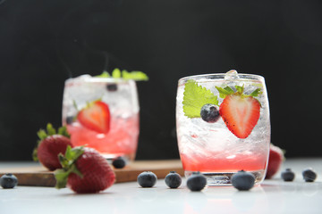 Strawberry juice cocktail with ice and mint on black background and smoke