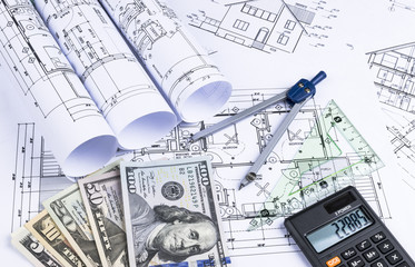 A blueprint of an architect with money, calculator. symbolic photo for financing and planning of a new house. Blueprints rolls and a drawing instruments on the worktable