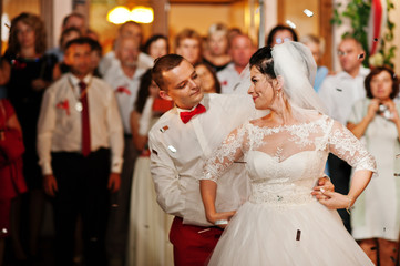 Fantastic wedding couple dancing their first dance in the restaurant with confetti.