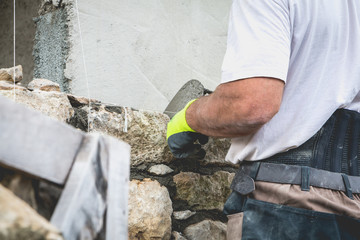 worker rides a stone wall on a traditional renovation site