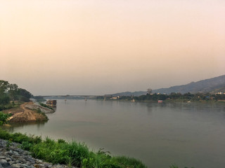 Mekong river and bridge crossing to Laos on evening with sunset and yellow sky. Big river at countryside with mountain and bridge on evening.