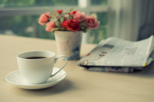 Cup of coffee with newspaper on the table in the morning , warm tone background