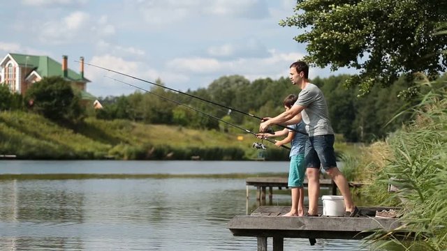 Dad and teenage boy angling together on lake