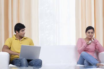 Man looking at woman while using laptop 