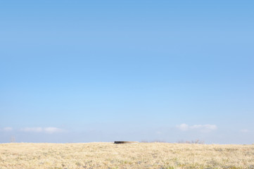 Fototapeta premium Dry grass field with a water well and blue sky