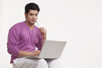 Serious young man using laptop 