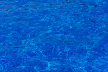 Close-up of crystal-clear water with sunshine in the swimming pool, background, texture. Swimming conception. Shallow depth on focus.