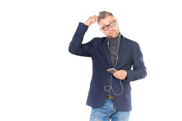 Middle adult man in eyeglasses listening to music on smartphone through earphones