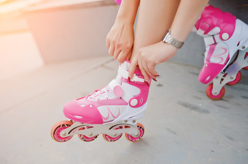 Young woman putting on rollerblades outdoor.