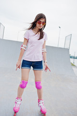 Portrait of a fabulous young woman rollerblading on the outdoor roller skating rink.