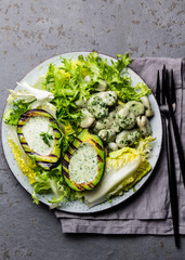 Vegetarian lettuce beans salad with grilled avocado and herb sauce. Top view