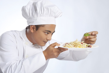 Chef placing leaf on plate of noodles