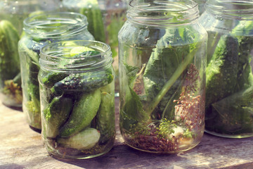 cooking salted delicatessen/ Cucumbers in glass jars for sunset on the table