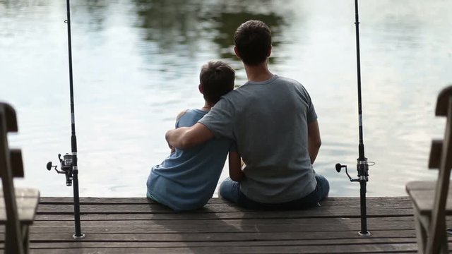 Affectionate father embracing son as they fish