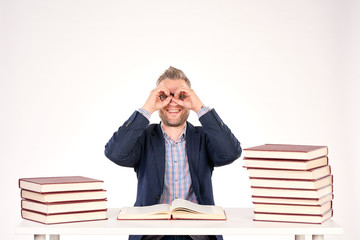 Portrait of middle-aged professor sitting at desk with book heaps on it