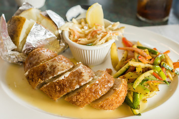 Stuffed breaded chicken and sauce, herbed vegetables, baked potato and coleslaw