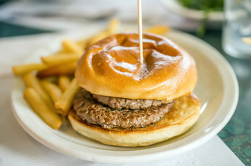 Juicy double hamburger with toasted bun held together with long pick, no condiments