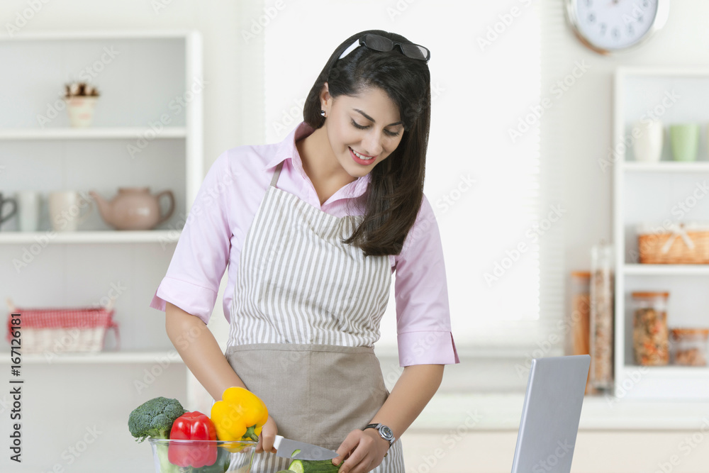 Wall mural businesswoman cutting vegetables in kitchen