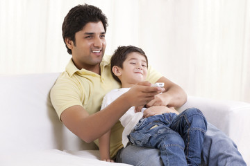 Happy father and son watching television 
