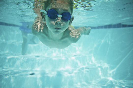 Shirtless boy swimming underwater in pool