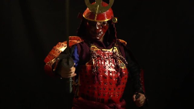 A samurai man in red armor and a defensive mask in the form of a demon stands with a katana in his hands, bit slow motion