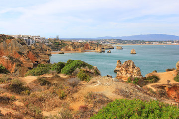 Fototapeta na wymiar Beautiful landscape overlooking Atlantic ocean coast in Lagos, south Portugal. Summer nature panoramic scene: hills, water, beach and blue sky background. Photo of long distance outdoor sunny day