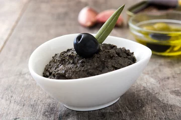  Black olive tapenade with anchovies, garlic and olive oil on wooden table   © chandlervid85