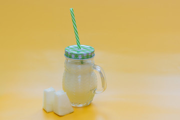 Melon smoothie in glass jar with two pieces of melon and green straw on yellow background