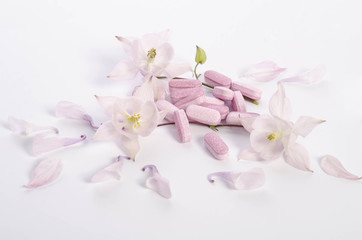 Alternative medicine tablets with flowers and petals on table