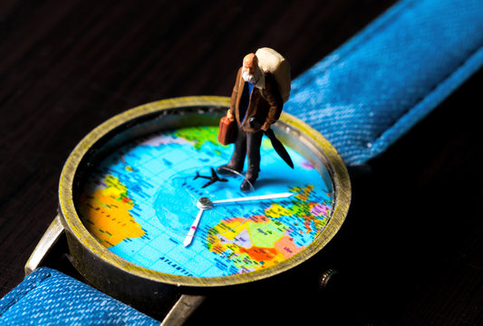 Old man on travel watches. World map travel photo banner. Aged traveler figurine.