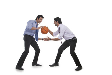 Two male executives playing basketball
