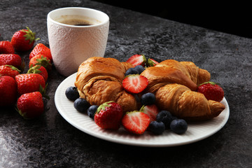 Delicious breakfast with fresh croissants and ripe berries on old marble background