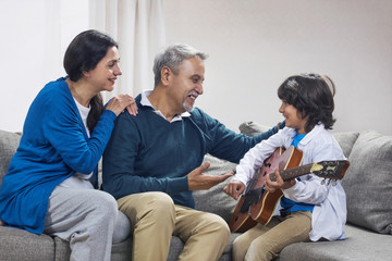 Grandson playing guitar with his grandparents