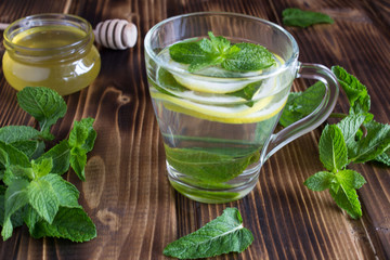 Tea with mint, lemon and honey on the wooden background